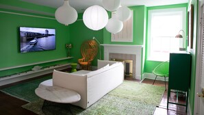 A living room with a green wall, a flat-screen TV, white furniture, and a fireplace. - Bosch Huis Rosé • Central • VIP • Parking (Savannah)