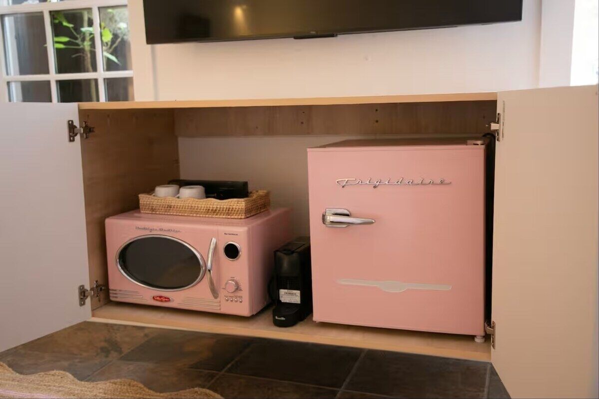 Eine Küche mit einem rosa Kühlschrank und einer Mikrowelle auf einer Holz Arbeitsplatte.