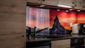 A modern kitchen with a stainless steel sink, a coffee maker, and a wooden cabinet. - Fabi s Horu Lodge (Zermatt)