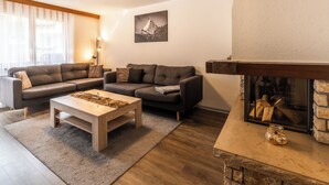 A living room with a sofa set, a coffee table, a fireplace, and a framed picture on the wall. - Fabi s Horu Lodge (Zermatt)