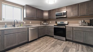 Una cocina moderna con armarios de madera, electrodomésticos de acero inoxidable y un ventanal que ofrece luz natural.
