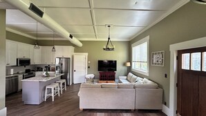 A spacious living area with a kitchen, a large sofa set, and a dining table. - THE BUNK HOUSE (Rock Spring)