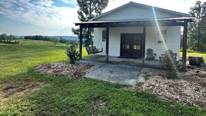 A white house with a porch, a swing, and a small tree in the yard. - THE BUNK HOUSE (Rock Spring)