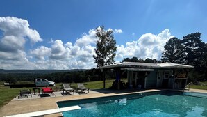 A clear blue pool with a covered seating area and a small building in the background. - THE BUNK HOUSE (Rock Spring)