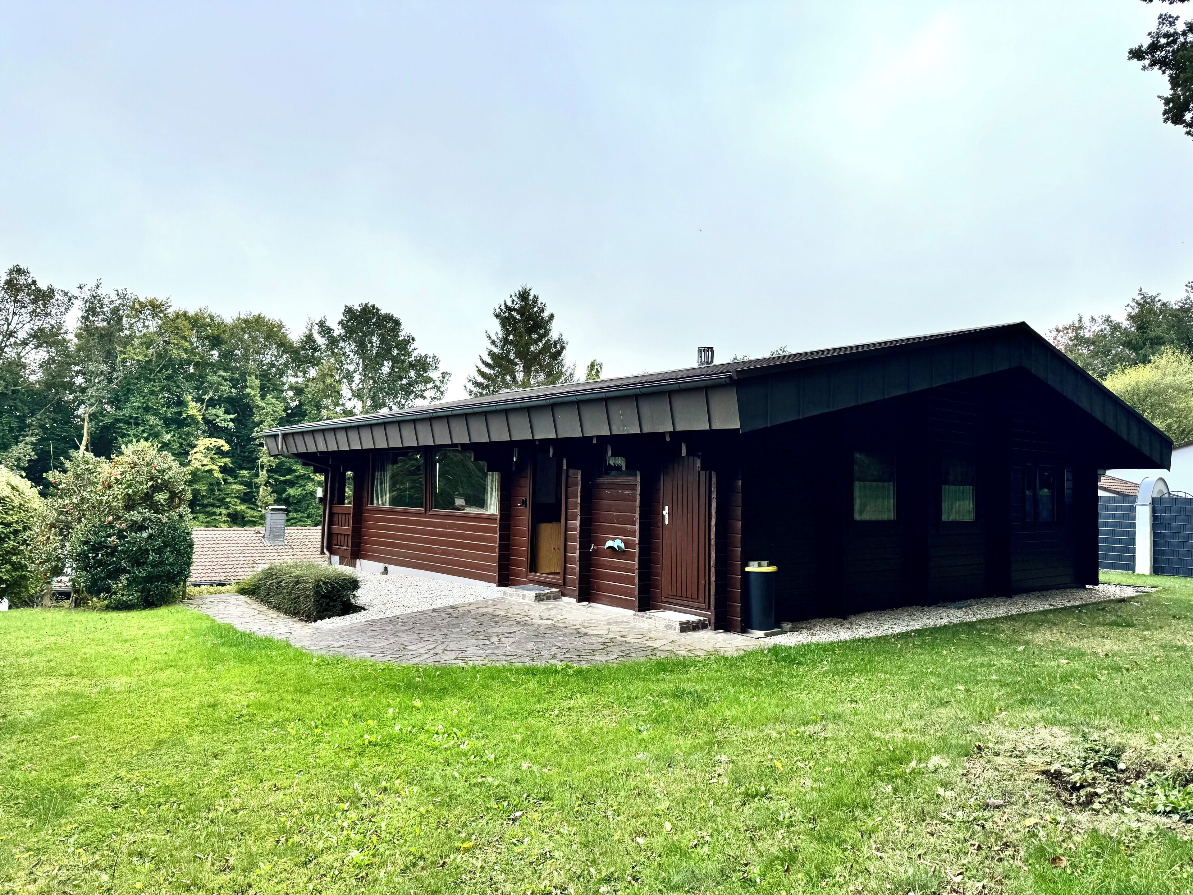 A modern building with a sloped roof and large windows, surrounded by a well-maintained lawn and trees.