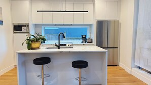 A modern kitchen with a central island, stainless steel appliances, and a window with a view. - Roger & May's Cabin in Vancouver (Vancouver)