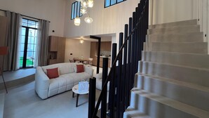 Un salon moderne avec un escalier, un coin repas et une cuisine.