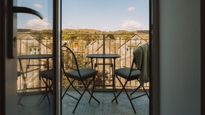 En balkon med to stole og et bord, der ud til et smukt udsigtspunkt over bygninger og bakker.