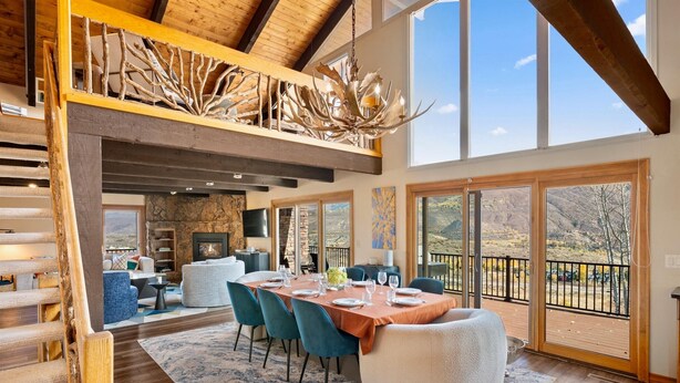 Un comedor espacioso con techos altos y luz natural, que cuenta con una chimenea, asientos cómodos y una vista panorámica a través de amplios ventanales.