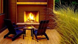 An outdoor deck with a wood-burning fireplace, two chairs, and a table. - The Laurel  A private retreat for two! Scenic mornings. (Fannin County)