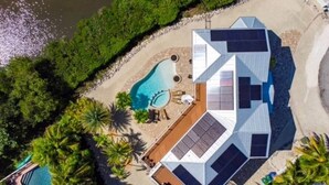 Eine Luftaufnahme eines modernen Hauses mit Swimmingpool, Solaranlage und angelegtem Garten.