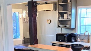 Uma cozinha com uma ilha de madeira, micro-ondas, máquina de café e pia.
