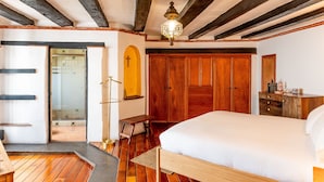 A bedroom with a wooden bed, a wooden wardrobe, and a bench.