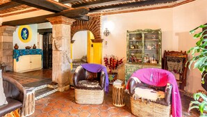 A cozy interior with a fireplace, leather armchairs, and a traditional wooden ceiling.