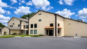 A multi-story building with a parking lot in front. - COUNTRY HOST INN (Franklin)