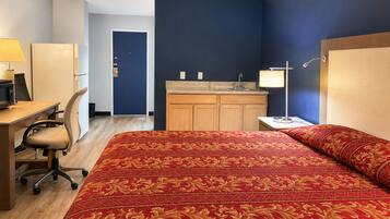 Ein Hotelzimmer mit Bett, Schreibtisch, Stuhl und Küchenzeile.