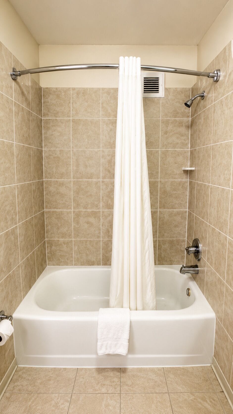 Une baignoire standard avec un rideau de douche, une serviette et une pomme de douche à main.