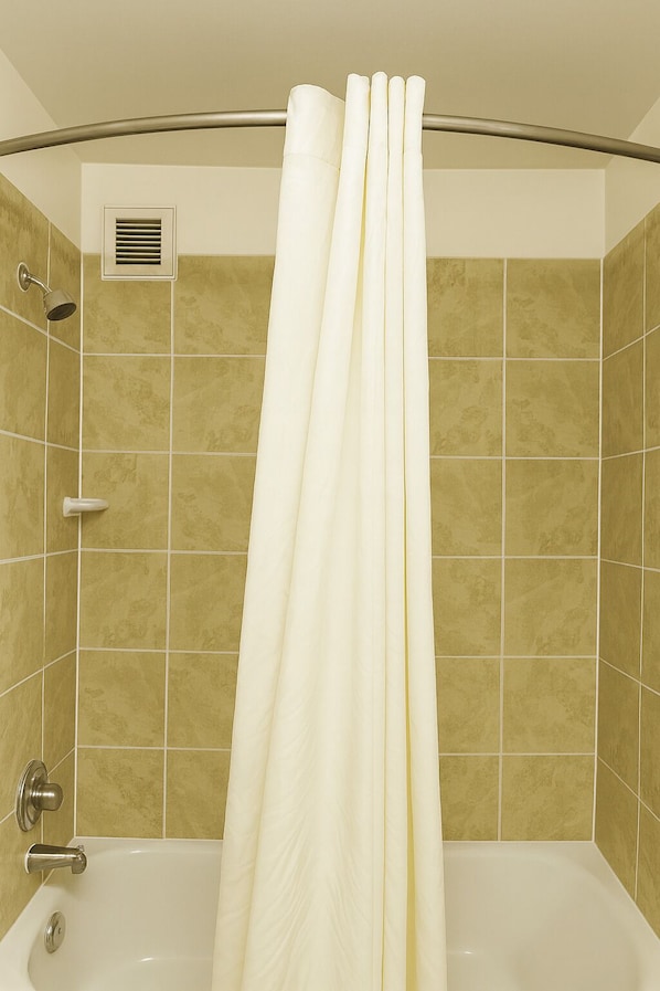 Bañera con ducha, toallas, jabón, shampoo