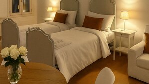 Un dormitorio con dos camas, vigas de madera en el techo, una mesita de noche con lámpara y una ventana con cortinas.