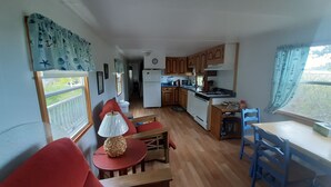 A compact living space with a kitchenette, a dining area with red furniture, and a view through a window.