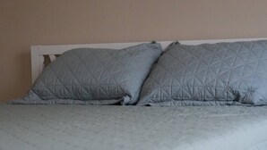 A bed with a quilted grey bedspread and pillows, a white headboard, and a plain wall. - Come Stay At The Orchard's Inn, 15 minutes away from Airport! (Summerville)