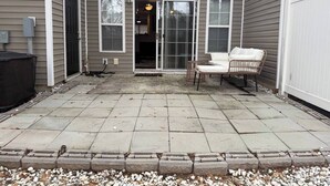 A patio area with a concrete floor, a sliding glass door entrance, and two wicker chairs. - Come Stay At The Orchard's Inn, 15 minutes away from Airport! (Summerville)