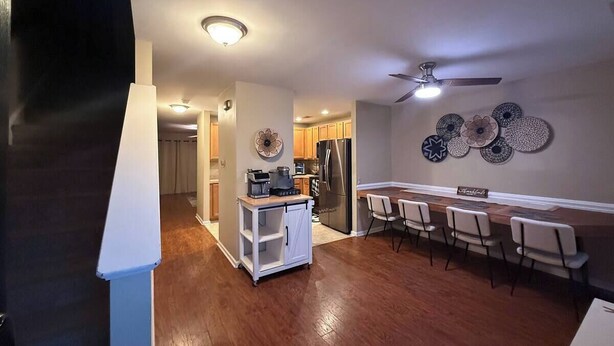 A modern kitchen with a refrigerator, a coffee maker, and a small island. There is a dining area with chairs and a table. - Come Stay At The Orchard's Inn, 15 minutes away from Airport! (Summerville)