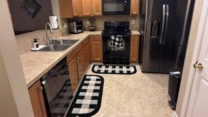 A compact kitchen with wooden cabinets, a stainless steel refrigerator, a microwave, an oven, and a dishwasher. - Come Stay At The Orchard's Inn, 15 minutes away from Airport! (Summerville)