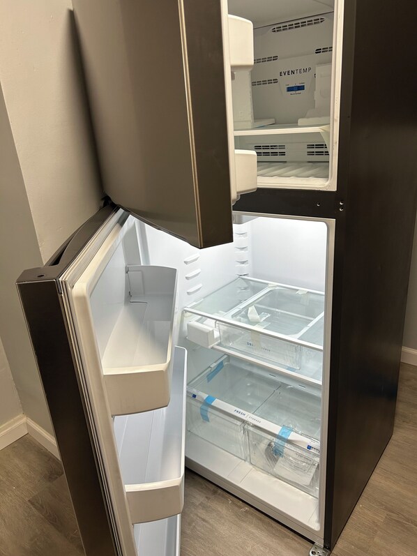 A modern, empty refrigerator with multiple shelves and a freezer compartment.