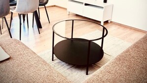 Uma sala de estar moderna com uma grande televisão de tela plana na parede, uma mesa de centro redonda de vidro e um sofá.