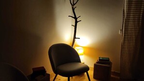 A dimly lit room with a modern chair, a small table, and a decorative branch on the wall. - XISTO Xisto, a haven for an unforgettable stay. (Semide)