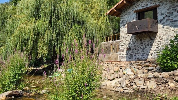 A rustic stone building with a wooden balcony, surrounded by lush greenery and a weeping willow tree. - XISTO Xisto, a haven for an unforgettable stay. (Semide)