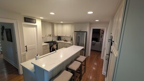 Una cocina moderna con armarios blancos, un refrigerador de acero inoxidable y una encimera de mármol.