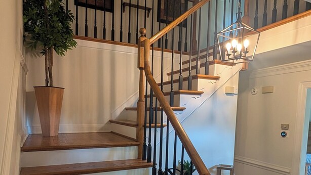 Una escalera de madera con barandilla y un candelabro en la parte superior.
