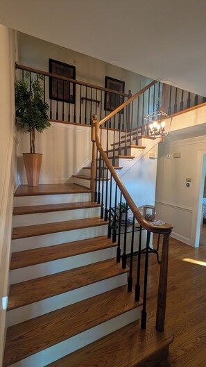 A wooden staircase with a handrail and a chandelier at the top. - Luxurious 5-bedroom executive home in premier Newport News neighborhood. (Newport News)