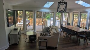 Un amplio espacio de estar con techo alto, tragaluces, una mesa de comedor y un sofá confortable.