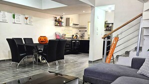 A modern living room with a grey sofa, a glass coffee table, and a dining area with black chairs and a pumpkin decoration. - Vane's House 5 minutes from the Consulate (Juárez)
