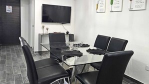 A modern meeting room with a glass table, black chairs, a flat-screen TV, and a ceiling light fixture. - Vane's House 5 minutes from the Consulate (Juárez)