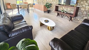 A modern living room with leather sofas, a marble coffee table, a stone accent wall, and a flat-screen TV. - Vane's House 5 minutes from the Consulate (Juárez)