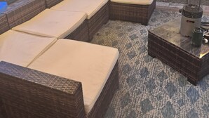 An outdoor patio with wicker furniture and a table with a grill.
