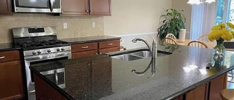 Una cocina con estufa de acero inoxidable, microondas y encimera de granito.