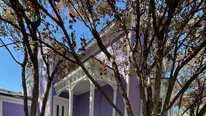 Une maison avec une véranda, un fauteuil suspendu et des arbres.