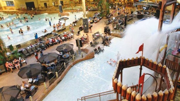 Ein großer Indoor-Wasserpark mit mehreren Pools, Rutschen und Sitzbereichen.