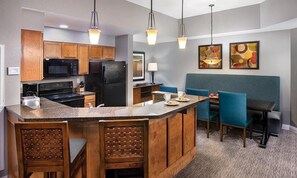 A modern kitchen with wooden cabinets, a granite countertop, and a built-in island with bar stools.