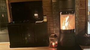 A cozy living room with a fireplace, a television on a cabinet, and a dog lying on the floor.