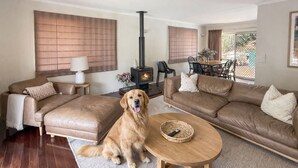 A living room with two sofas, a dog, a fireplace, and a dining area. - Spacious Family Retreat with Pool/Pet friendly (Kenmore)