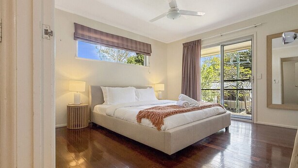 A bedroom with a bed, a ceiling fan, a window with curtains, a nightstand, and a view of the outdoors. - Spacious Family Retreat with Pool/Pet friendly (Kenmore)
