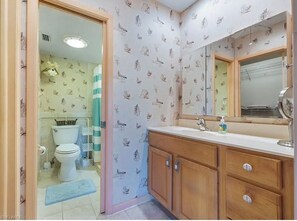 A bathroom with a toilet, sink, and mirror. The walls have a bird pattern wallpaper. - Location location location (Naples)