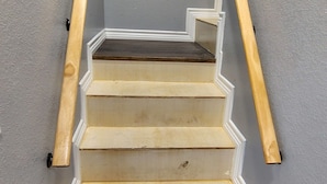 Una escalera con escalones blancos y barandillas de madera que conduce a una plataforma.