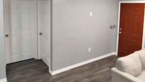 Una habitación con paredes grises, piso de madera, una puerta blanca y una puerta marrón.